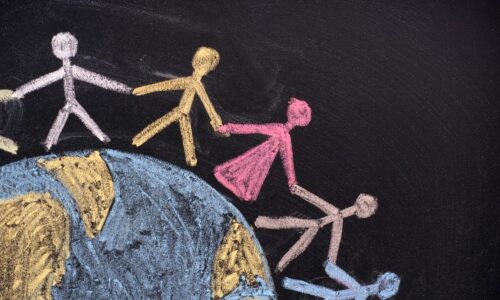 Chalk drawing of stick figures holding hands in a chain, standing on a globe, representing community support