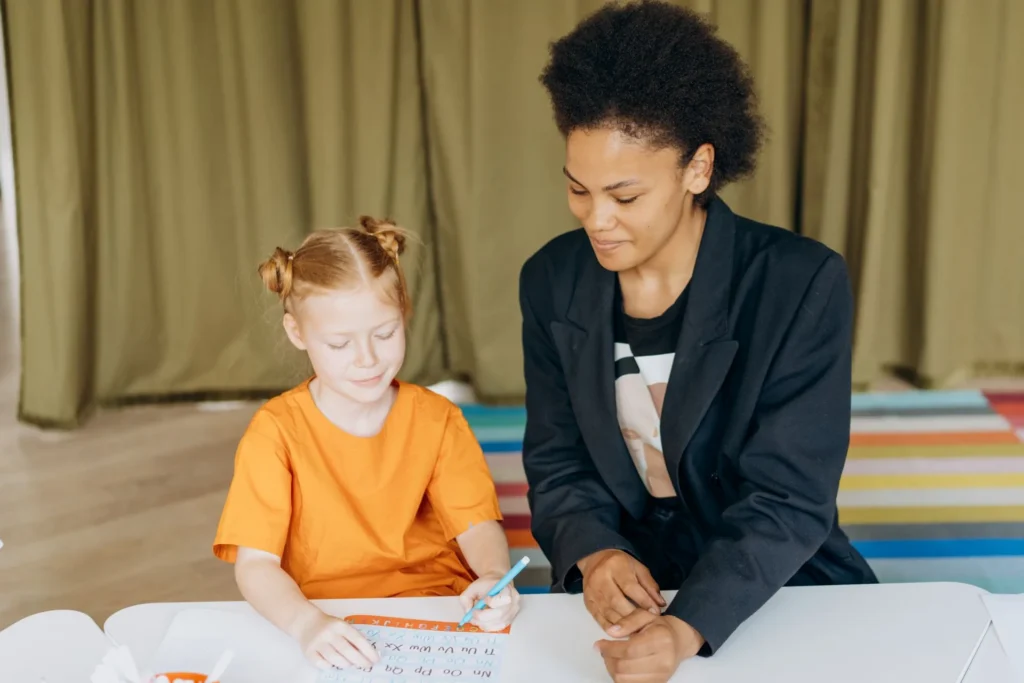 A qualified behavior analyst (QBA) following a child's performance during a structured assessment activity at a table