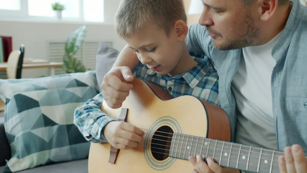 أب يعلّم ابنه العزف على الجيتار في البيت
